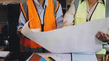 Two people in safety vests holding papers and looking at them video