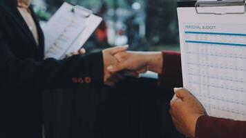 Two people shaking hands over a clipboard with a list of names video