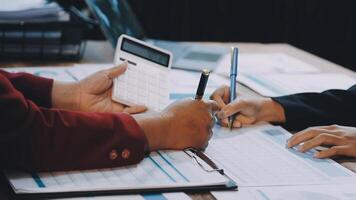 Two business people are working on paperwork and a calculator video