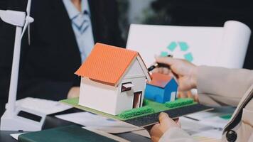 A man holding a model of a house and a woman holding a paper with a recycling symbol video