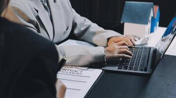A man in a suit is typing on a laptop video