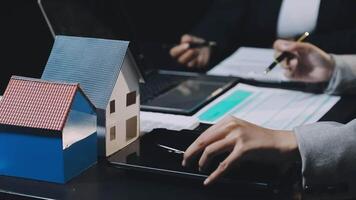 A person is using a laptop and a house model video