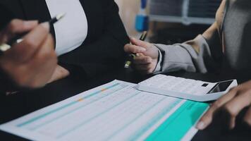 Two business people are working on paperwork with a calculator video