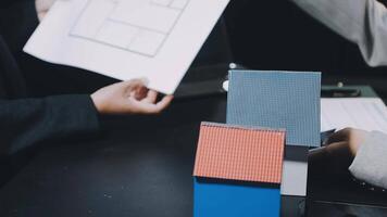 Two people holding blueprints and a house model video