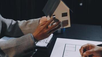 Two people holding a house model on a table video
