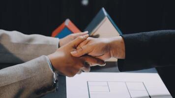 Two people shaking hands over a table with a house model video