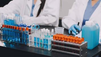 Two women in lab coats working on a table with test tubes video