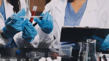 Two women in lab coats holding up a test tube video