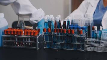 dois pessoas dentro laboratório casacos estão trabalhando em uma mesa com teste tubos video