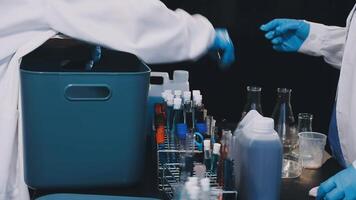 Two people in lab coats and gloves working on a table video
