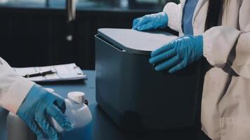 Two people in lab coats and gloves are holding a container video