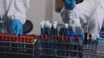 Two people in lab coats and gloves are working on a table video