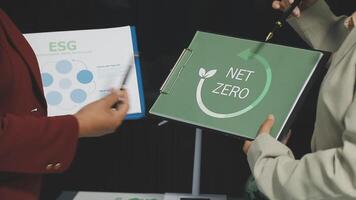 Two people holding a folder with the word net zero on it video