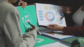 Two people are looking at a paper with the words net zero on it video