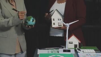 Two people holding a house and a wind turbine video