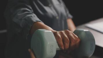 A person holding two dumbbells in front of a desk video