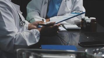 Two doctors are sitting at a table with a clipboard video