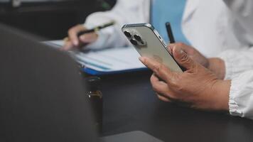 A doctor is using a smartphone while sitting at a desk video