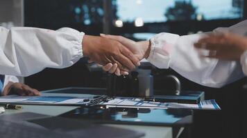 Two people shaking hands over a table with papers video