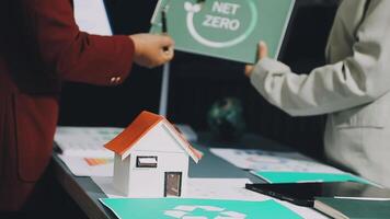 Two people holding a net zero sign and a house with a recycling symbol video