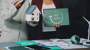 Two business people holding up a house with a net zero sign video