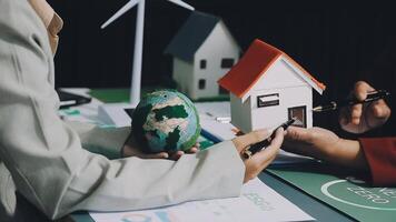 Two people are holding a model of a house and a globe video