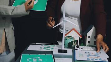 Two people working on a table with paper and wind turbines video