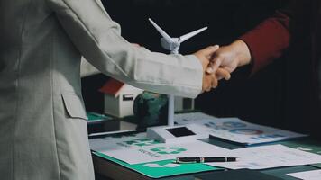 Business people shaking hands over a table with wind turbines video