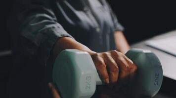 A person holding two dumbbells in front of a desk video