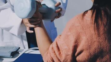 A woman is holding a dumbbell while a doctor is looking at her video
