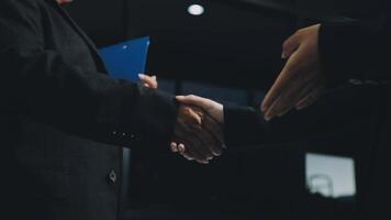 Two business people shaking hands in front of a dark background video