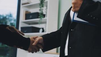 Two business people shaking hands in an office video