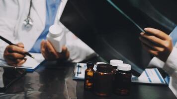 Two doctors are working on a laptop with bottles and pills video