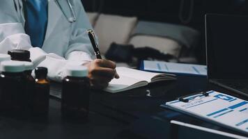 A doctor is writing on a notebook while sitting at a desk video