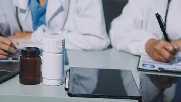 Two doctors sitting at a table with a tablet and bottle video