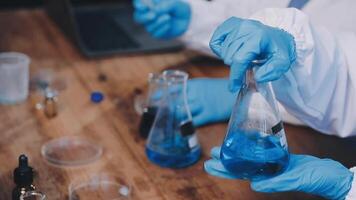 A person in a lab coat holding a blue liquid video