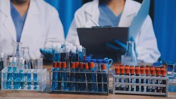 Two people in lab coats standing next to a table with test tubes video