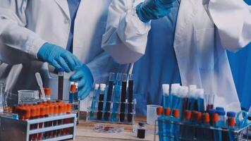 Two people in lab coats and gloves are working on a table video