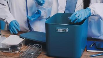 Two people in lab coats and gloves are working on a table video
