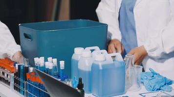 Two people in lab coats working on a table with bottles and other supplies video