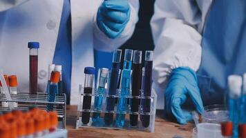 Two people in lab coats and gloves are working on a table video