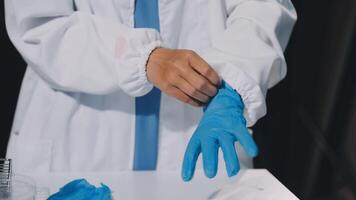 A person in a lab coat is putting on blue gloves video