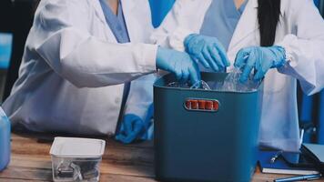 Two people in lab coats and gloves are putting something into a container video