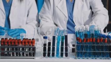 Two people in lab coats are working on a table with test tubes video