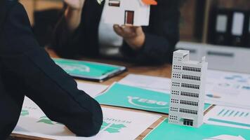 A man and woman are sitting at a table with paper models of buildings video