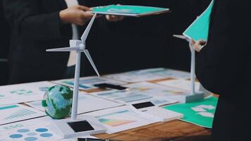 Business people standing around a table with wind turbines video