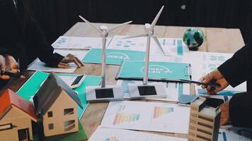 Two people are working on a table with papers and wind turbines video