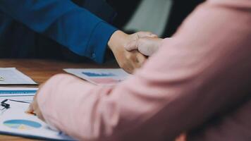 Two people shaking hands over a table with papers video