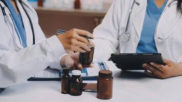 Two doctors are working on a tablet with bottles video