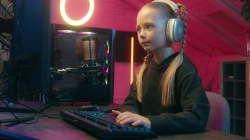 Serious teenager little girl concentrated web net streaming daughter child kid playing computer monitor match play talking to microphone broadcasting speak game online gaming stream at home neon video